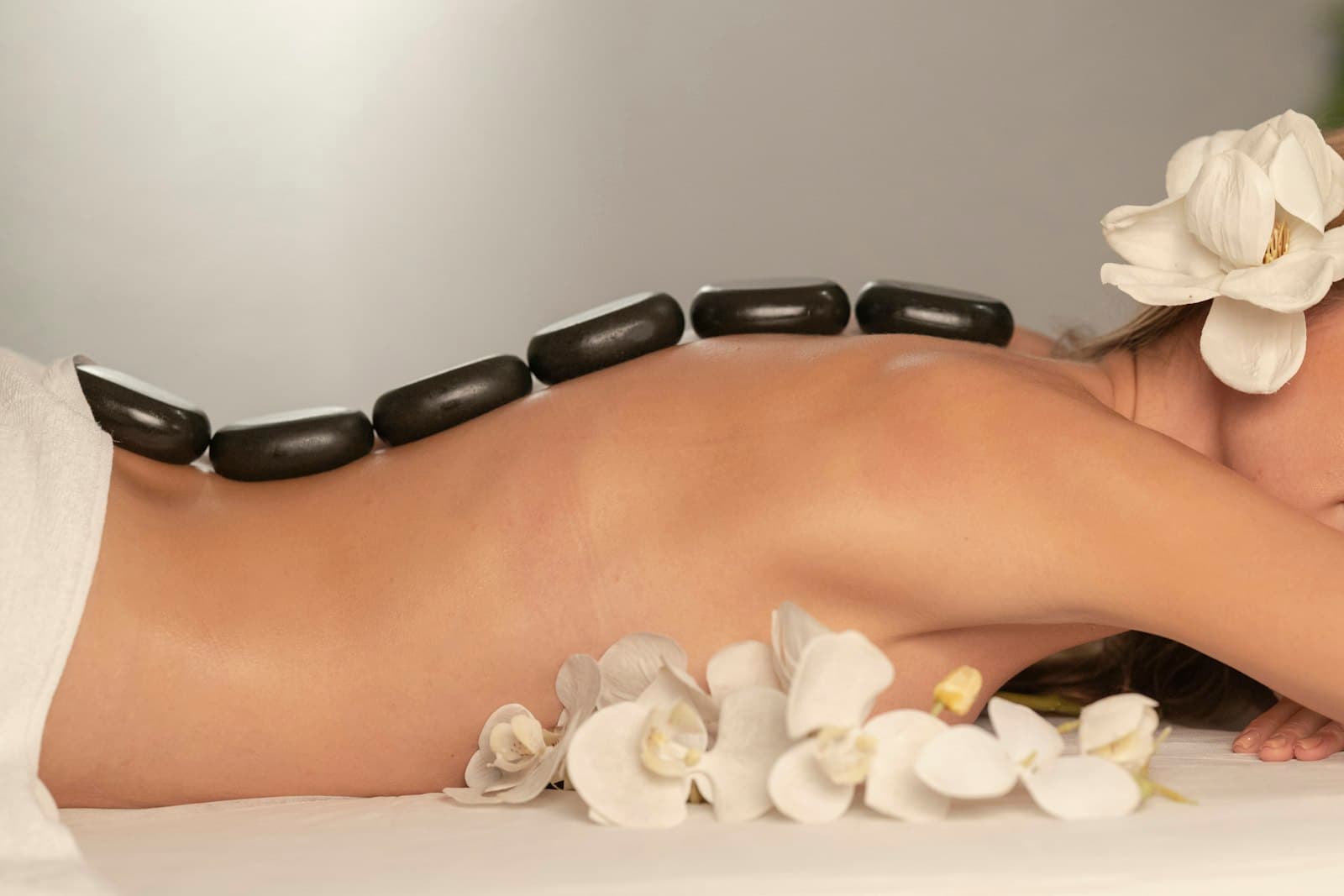 Hot stone massage treatment with orchid flowers
